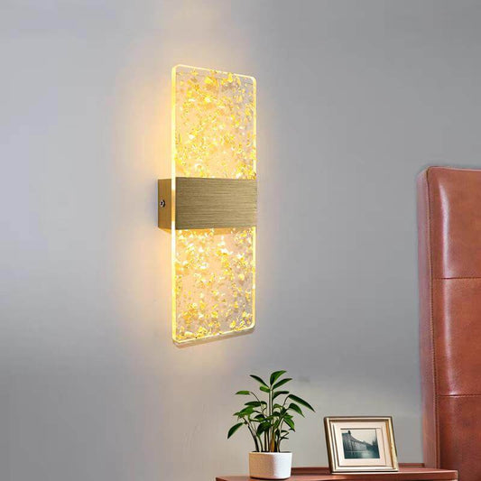 Modern LED wall lamp with acrylic shade and brushed aluminum base illuminating a bedroom wall.