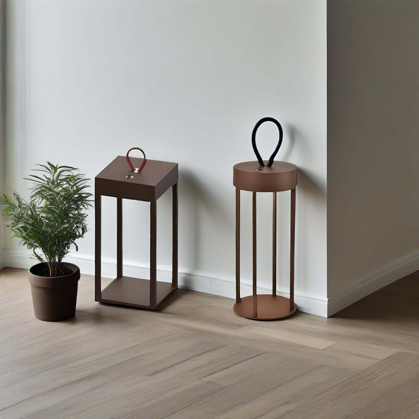 Two modern portable table lamps in brown, one with a handle, and a potted plant beside them.