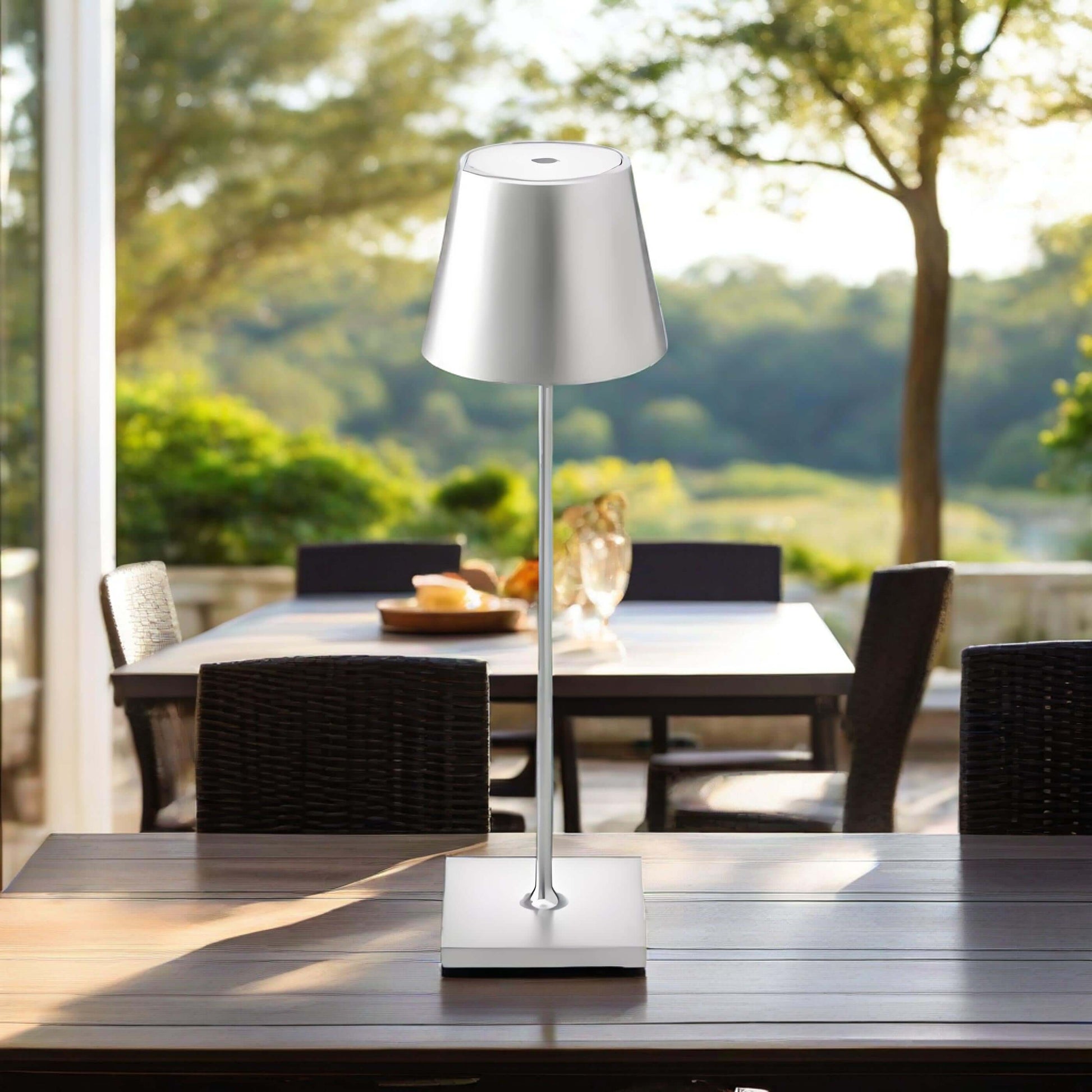 Rechargeable wrought iron stemmed cup desk lamp on a patio table, providing adjustable reading light in natural setting.