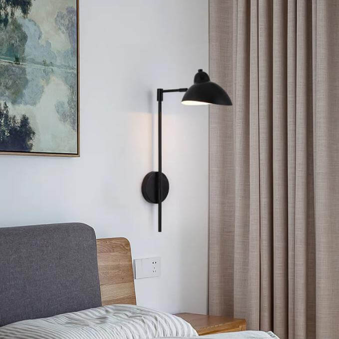Vintage swing arm wall lamp in a cozy bedroom setting, featuring black metal design and adjustable shade for reading.